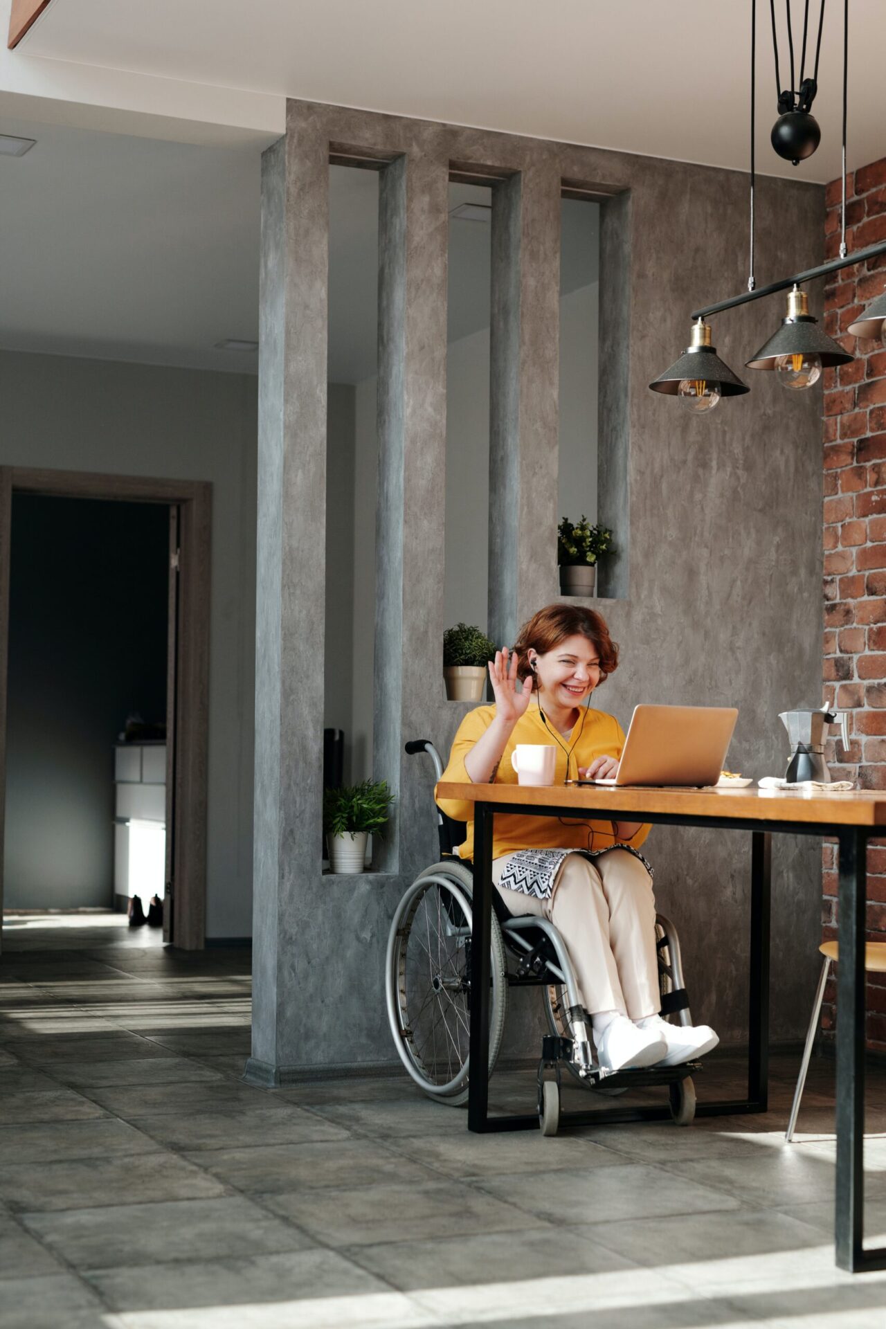 Young adult woman in a wheel chair waving on a zoom meeting - donate